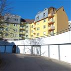 Vícepodlažní bytový dům s barevnou fasádou a balkonem, moderní architektura, umístění v klidné rezidenční čtvrti.
